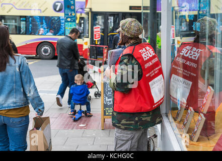 Woman on the streets as an official vendor of the Big Issue magazine in Brighton, East Sussex, England, UK. Stock Photo