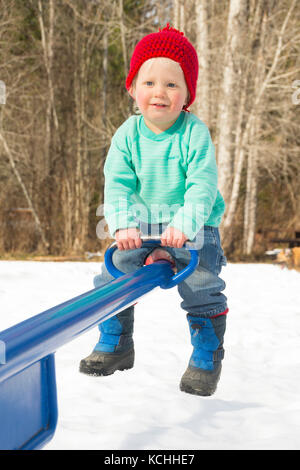 A two-year boy playing old on a teeter-totter in the winter Stock Photo