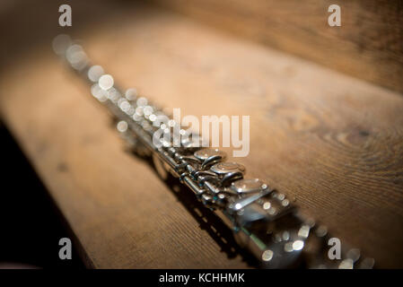 A complete silver alto flute isolated against a wooden background. Stock Photo