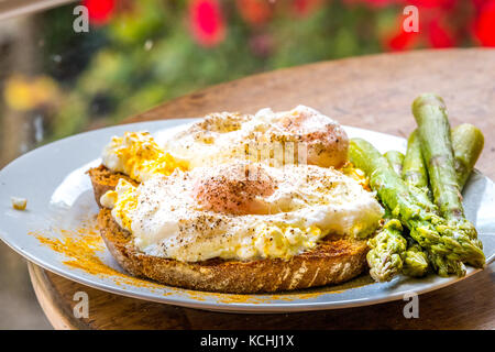 Poached Egg with turmeric on toasted sourdough bread with asparagus Stock Photo