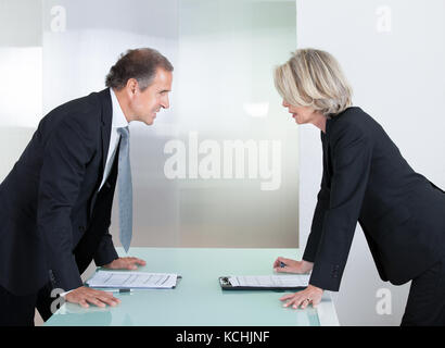 Mature Businessman And Businesswoman Looking At Each Other With Angry Stock Photo