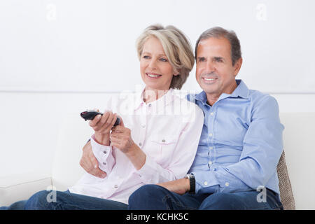 Happy Mature Couple Watching Television At Home Stock Photo