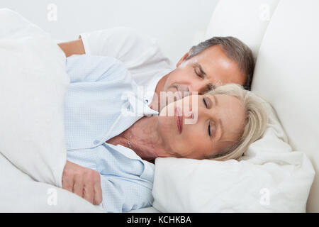 Portrait Of Happy Senior Couple Sleeping Together In Bed Stock Photo