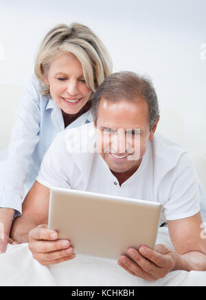 Happy Mature Man Using Digital Tablet Woman Looking From Behind Stock Photo