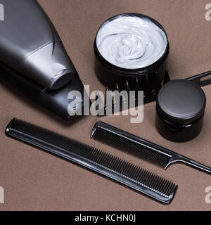 Different hair styling products and accessories to create beautiful hairstyle. Cosmetics and various kinds of combs on brown textured surface Stock Photo