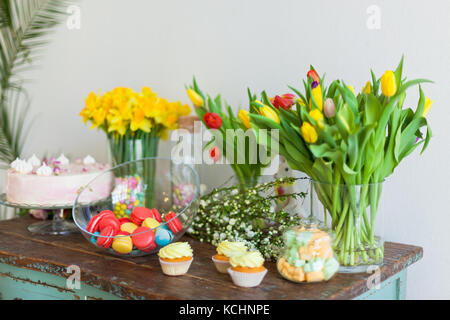 Bright macaroons and cupcakes on a wooden table. Indoors natural light shot with small depth of field Stock Photo