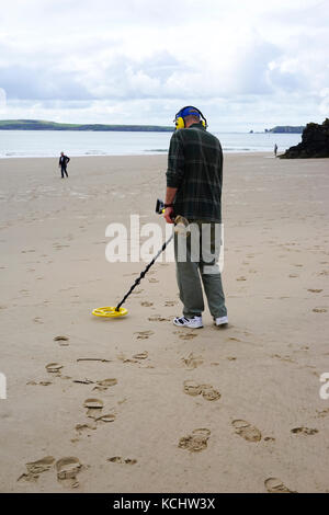 Man using a metal detector on Tenby Beach, South Wales, UK. Stock Photo