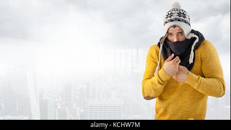 Digital composite of Man keeping warm in hat and scarf in bright city Stock Photo