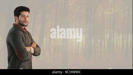 Digital composite of Man in Autumn with folded arms in muted forest Stock Photo