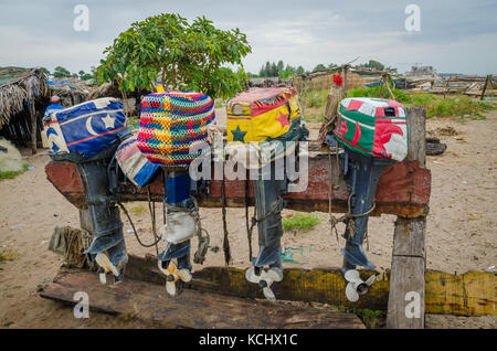 Colorful lined up fishing boat engines with artistic covers on wooden stand, The Gambia, West Africa Stock Photo