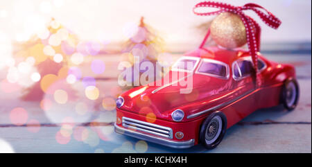 Toy car carrying christmas bauble ball on wooden plank during christmas time Stock Photo