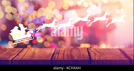 Silhouette of santa claus and reindeer against composite image of wooden shelf against christmas tree Stock Photo