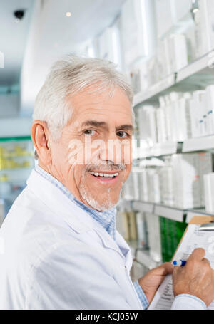 Smiling Senior Pharmacist Counting Stock In Drugstore Stock Photo