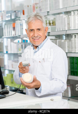 Portrait Of Pharmacist Scanning Barcode Of Shampoo Bottle Stock Photo
