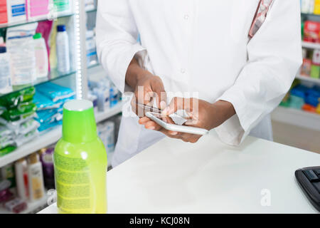 Female Pharmacist Using Smartphone Credit Card Reader At Counter Stock Photo