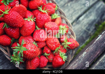 Strawberry in wicker plate on wooden background Stock Photo