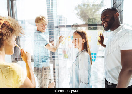 Excited cheerful colleagues discussing new business strategies Stock Photo