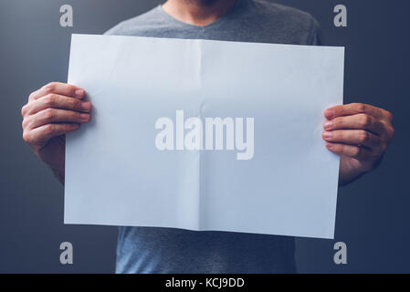 Casual man holding blank A3 paper spread as copy space for magazine and newspaper text or graphic design mock up Stock Photo