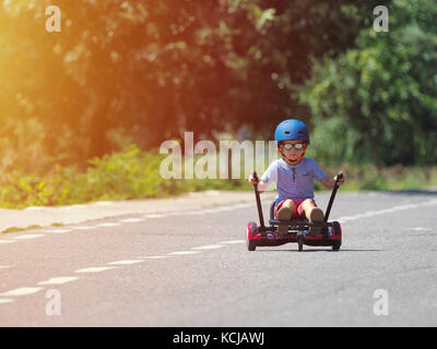 Happy boy standing on hoverboard or gyroscooter with kart accessory kit outdoor. New modern technologies Stock Photo