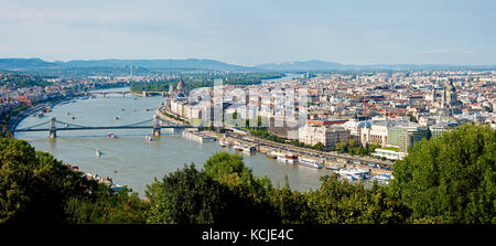 A 3 picture stitch panoramic cityscape view of the Danube river in Budapest on a sunny day and blue sky with the Chain Bridge foreground. Stock Photo