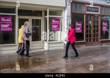 Out of focus figures passing, Businesses in decline,  Prime Location, Retail Units, May Sell, All enquiries, Stores To Let, retail units, closed, closing down after poor retail sales, shuttered shops,  Chapel Street, & Lord Street, Southport, Merseyside, UK Stock Photo