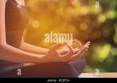 Close-up of feminine and masculine arms and crossed legs during meditation with nature background. Stock Photo