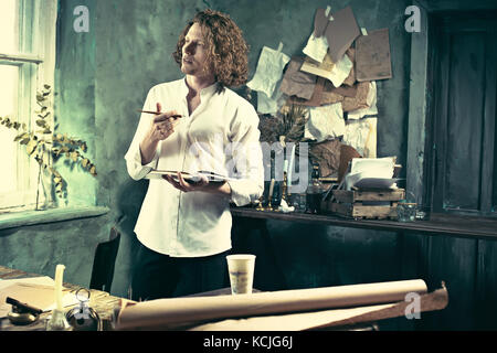 Writer at work. Handsome young writer standing near the table and making up something in his mind Stock Photo