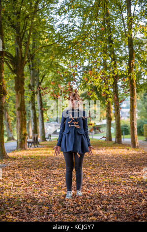 Blonde girl throwing yellow leaves, Luxembourg Stock Photo