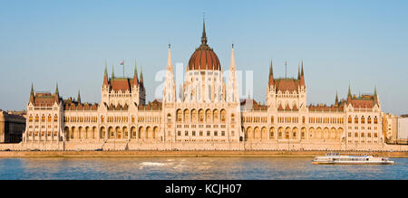 A 3 picture stitch panoramic view of the Hungarian Parliment Building on the Danube river in Budapest with a river boat cruise vessel going past. Stock Photo