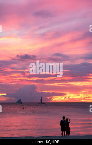 Philippines sunset - a  couple watching sunset at  Boracay beach, Boracay, Philippines Asia Stock Photo