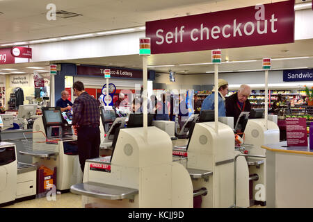 Rows of self service check out tills in supermarket with sign above Stock Photo