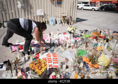 Las Vegas, USA. 05th Oct, 2017. Victoria Minarcik places a sign on a makeshift memorial for the victims of the Route 91 Harvest Country Music Festival mass shooting on the Strip in Las Vegas, Nev., Oct. 5, 2017. Credit: Jason Ogulnik/Alamy Live News Stock Photo