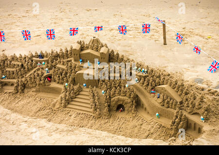 A detailed sandcastle sculpture, surrounded by small Union Jack flags, on an urban beach on the South Bank of the River Thames, London, England, UK. Stock Photo