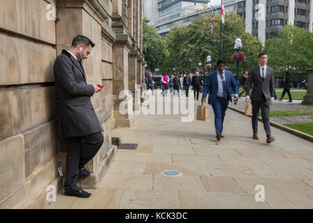 Smart dressed business man using mobile phone in central Birmingham UK Stock Photo