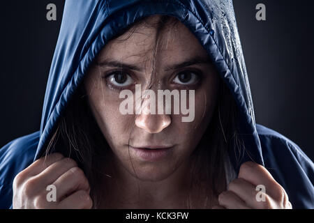 Sweaty Woman with Blue Raincoat Holding a Hood Stock Photo