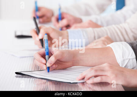Business People Sitting In A Row And Writing Notes In Office Stock Photo