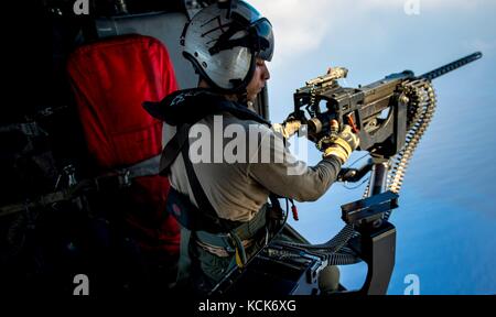 A U.S. sailor mans a GAU-21 .50 caliber rapid-fire machine gun from a U.S. Navy MH-60S Seahawk helicopter in flight July 20, 2017 over the Mediterranean Sea.  (photo by MCSS Zachary Wickline  via Planetpix) Stock Photo