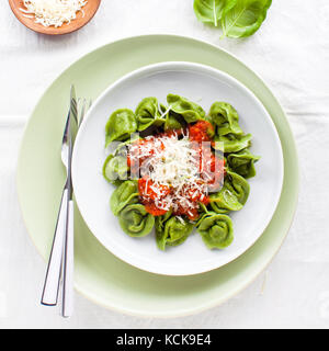 classic homemade Italian tortellini with spinach and ricotta, spring style and red wine in wineglass Stock Photo
