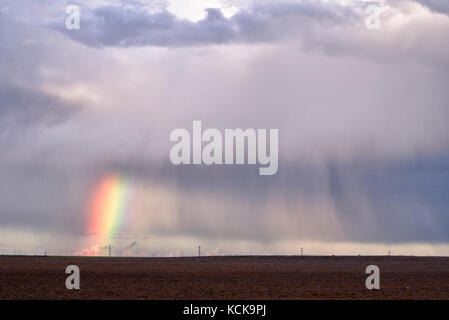 Rainbow and cloud discharging water over the fields Stock Photo