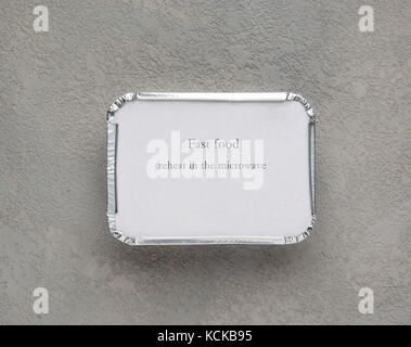 fast food in a foil box on a gray rough background. food for businessman and busy people Stock Photo