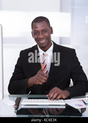 Happy Young African Businessman Using Computer At Desk Stock Photo