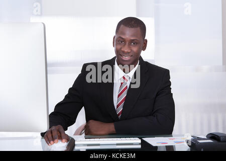 Happy Young African Businessman Using Computer At Desk Stock Photo