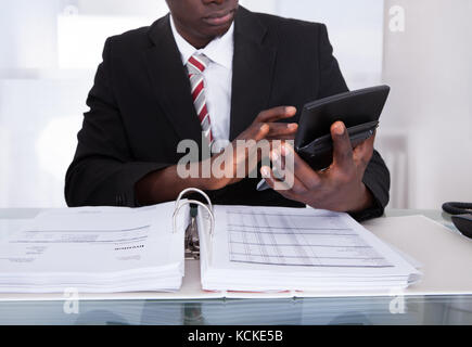 Close-up Of An African Businessman Doing Calculations Using Calculator Stock Photo