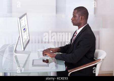 Portrait Of Young African Businessman Using Computer Stock Photo