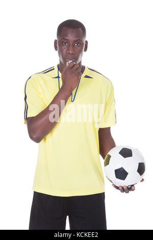Soccer Referee Holding A Ball With A Whistle In His Mouth Stock Photo