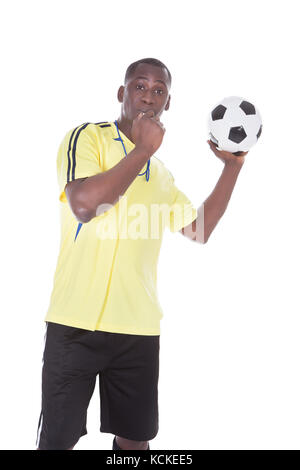 Soccer Referee Holding A Ball With A Whistle In His Mouth Stock Photo