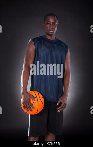 African Young Man With Basketball Over Black Background Stock Photo