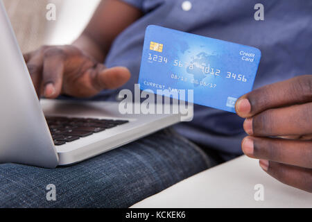 Close-up Of Hand Holding Laptop With Credit Card Stock Photo