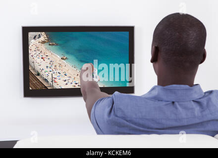 Rear View Of African Man Changing Channel With Remote Stock Photo