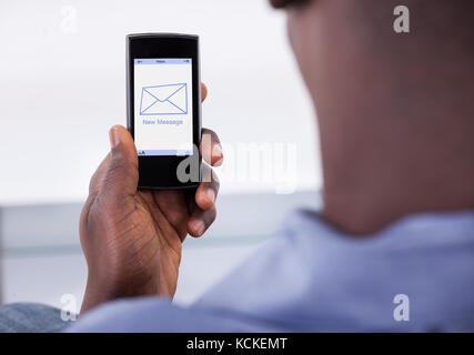 Close-up Of Person Holding Mobile Phone With One New Message Showing On A Screen Stock Photo